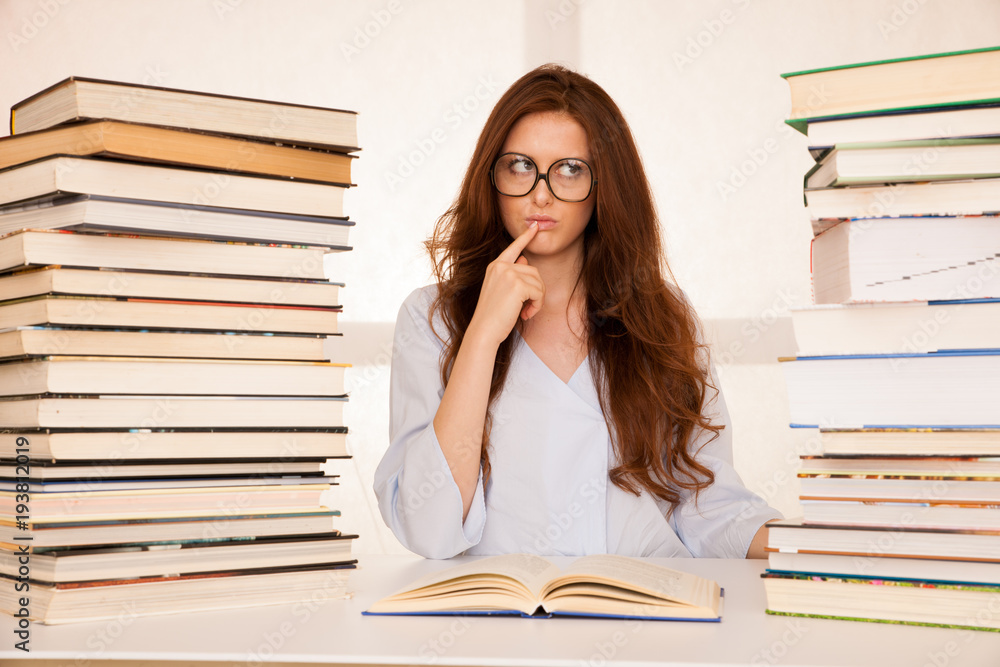 attractive young woman studies wtih hugr book piles on her desk attractive young woman studies wtih hugr book piles on her desk