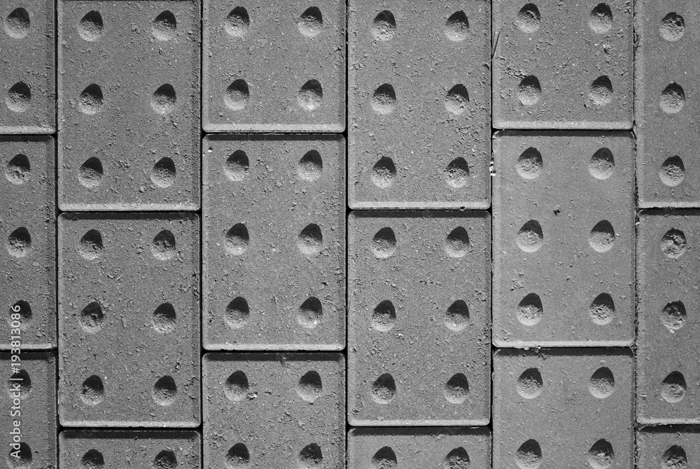 Fototapeta premium Tactile paving bricks with shadow detail photographed and processed in black and white to provide an abstract background