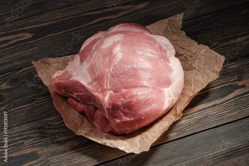 A piece raw pork shoulder. Pork tenderloin on paper on a dark background photo