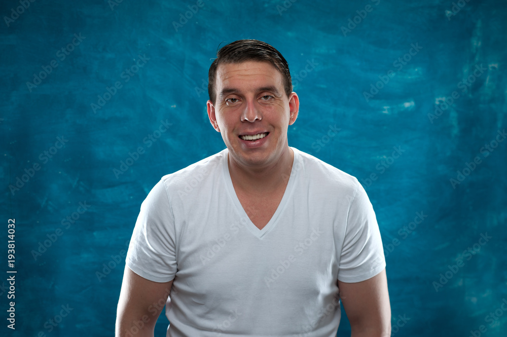 Close-up portrait of positive man in white shirt posing on blue background. Close-up portrait of positive man in white shirt posing on blue background.