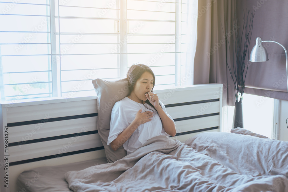Young asian woman coughing and sitting on her bed,Concept of health Young asian woman coughing and sitting on her bed,Concept of health