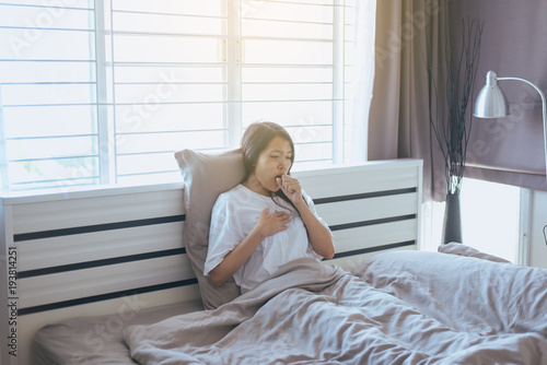 Young asian woman coughing and sitting on her bed,Concept of health