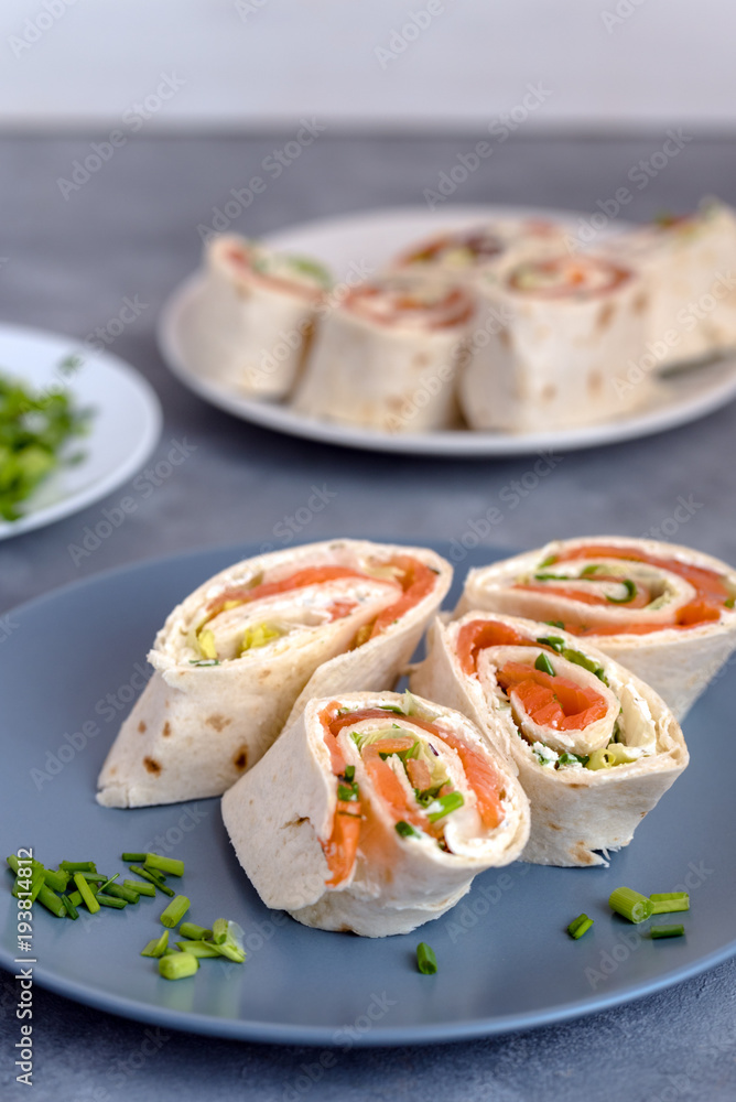 Rolls of thin pancakes with smoked salmon, cream cheese, chives and lettuce.