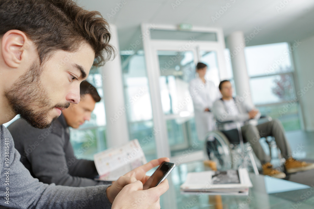 Fototapeta premium man using mobile phone while waiting a at clinic