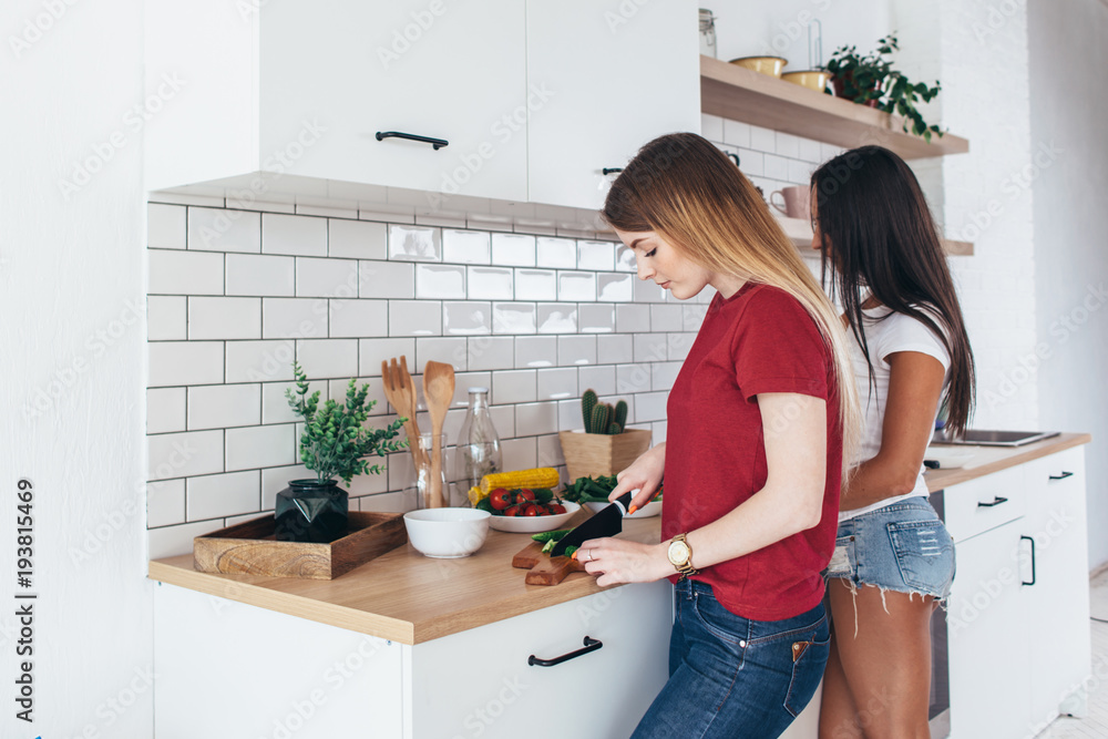 Young women in kitchen preparing food salad for lunch Young women in kitchen preparing food salad for lunch