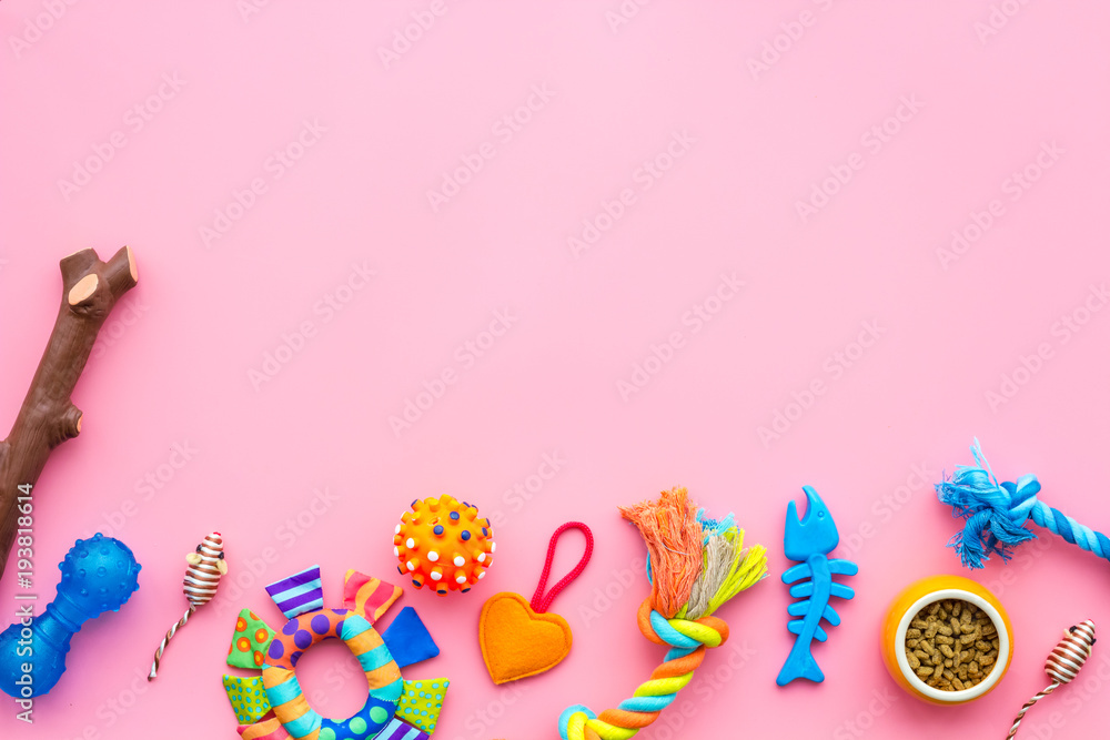 Obraz premium Pet care concept. Toys near bowls with animal feed on pink background top view copy space
