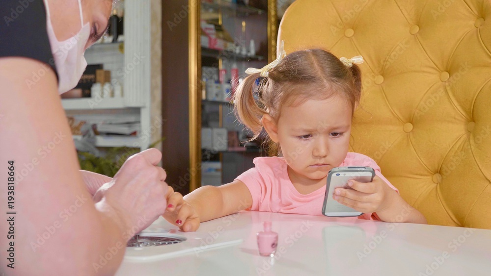 Beautician applying nail polish to kid's nail in a nail salon. Beautician applying nail polish to kid's nail in a nail salon.