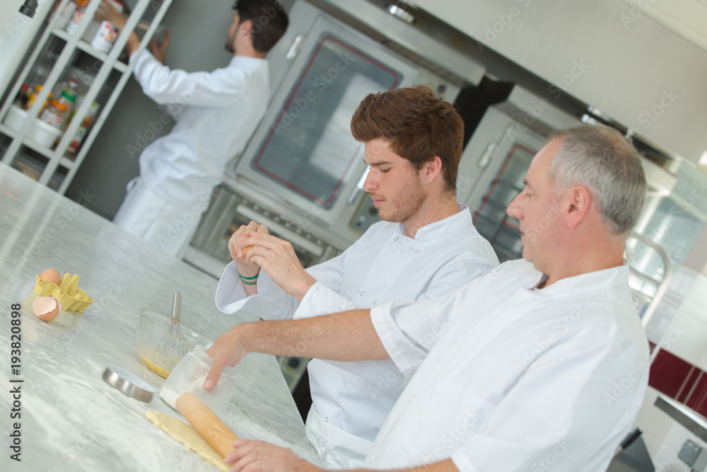 Obraz premium professional cook working with assistant