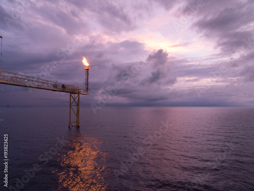 Fotografia, Obraz Fire on flare blow out in Offshore oil and Gas central processing platform and remote platform produced oil, natural gas and liquid condensate for set to onshore refinery from offshore in ocean sea
