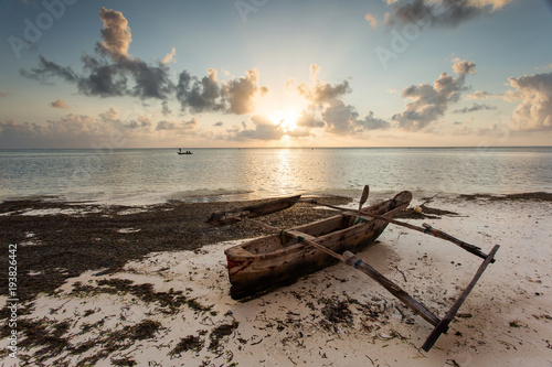 Fishermen going on ocean on traditional fishing boat in Zanzibar with storm clouds at sunrise