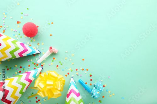 Birthday party caps, blowers and confetti on mint background
