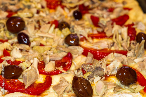 cooking homemade pizza with peppers, plums, ham, sausage, cheese and spices, closeup