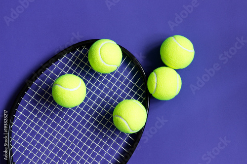 Tennis balls on black racket. Violet background. Concept sport. © Olha Kozachenko