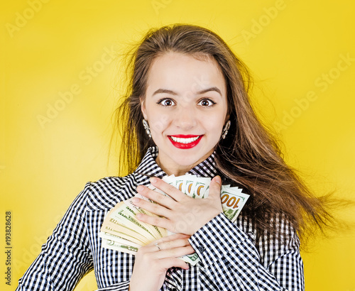 Slika na platnu Closeup portrait of a super happy excited successful business woman, funny looking face, holding money dollar bills in hand, isolated yellowphone