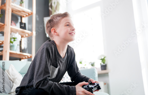 Excited young boy playing game on the console at home