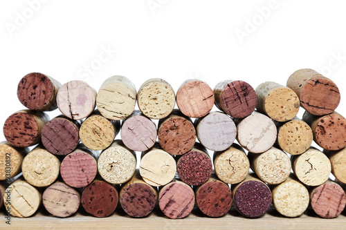 Multicolored bright corks from wine bottles on a wooden table isolated on a white background. Rows of corks with stain of red wine.