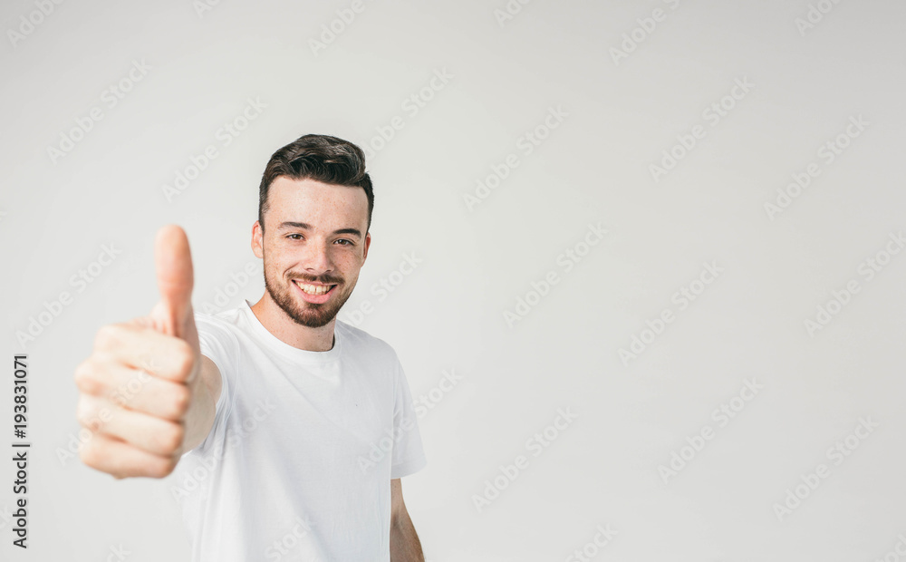 A man standing on the left side of a frame looking straight to the camera and showing his big thumb up to it. He looks cheerful and happy. A man standing on the left side of a frame looking straight to the camera and showing his big thumb up to it. He looks cheerful and happy.