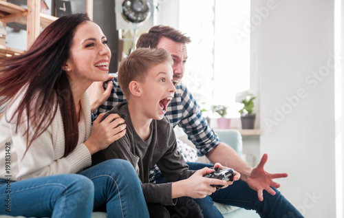 Billede på lærred Excited family playing video game on the console at home