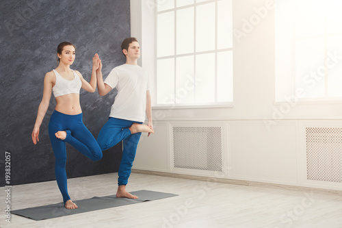 Couple training yoga in balance pose.
