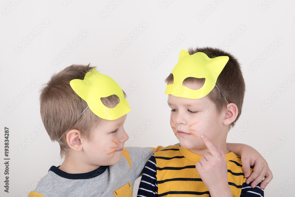 Happy children in elegant yellow clothes play at home. Boys in feline masks posing for a fashion magazine Happy children in elegant yellow clothes play at home. Boys in feline masks posing for a fashion magazine