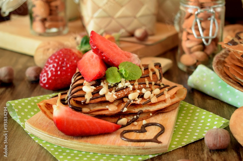 Crepes decorated with nuts, chocolate, fresh strawberries and mint