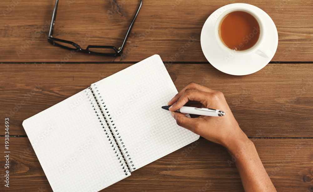 Black female hands writing in notebook, top view Black female hands writing in notebook, top view
