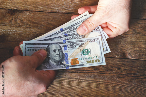 Canvas Print Hands transferring money on wooden background