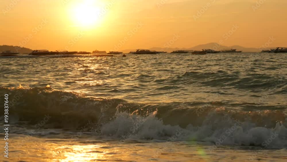 Scenic red sunset on the beach against the backdrop of the mountains. The waves of sea beat against the shore in the evening. Pleasure boats on the sea Scenic red sunset on the beach against the backdrop of the mountains. The waves of sea beat against the shore in the evening. Pleasure boats on the sea