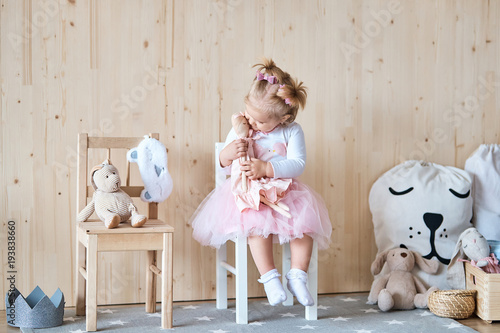 Photographie Amazing little girl playing with a doll in her room
