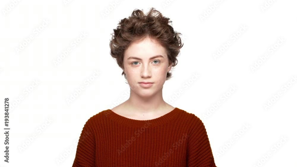 Studio portrait of confident lady with brown curly hair expressing agreement with nodding positively, over white background. Concept of emotions Studio portrait of confident lady with brown curly hair expressing agreement with nodding positively, over white background. Concept of emotions
