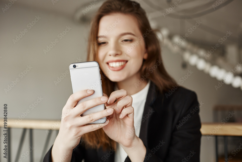 Age of technology is rising. Portrait of charming fashionable girl in cafe, smiling while browsing in internet or messaging via smartphone, waiting for girlfriends to have lunch together Age of technology is rising. Portrait of charming fashionable girl in cafe, smiling while browsing in internet or messaging via smartphone, waiting for girlfriends to have lunch together