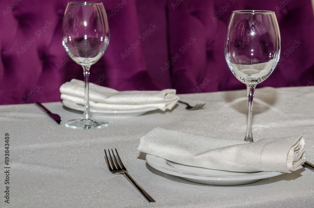 on the table with a white tablecloth is a cutlery for two that is made up of forks, knives, plates, glasses for wine, white napkins on the table with a white tablecloth is a cutlery for two that is made up of forks, knives, plates, glasses for wine, white napkins