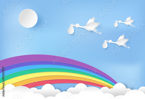 Paper art of stork flying with baby and rainbow on blue sky paper cut style illustration