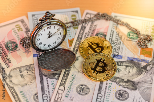 Two physical golden bitcoins with pocket watch on us dollars