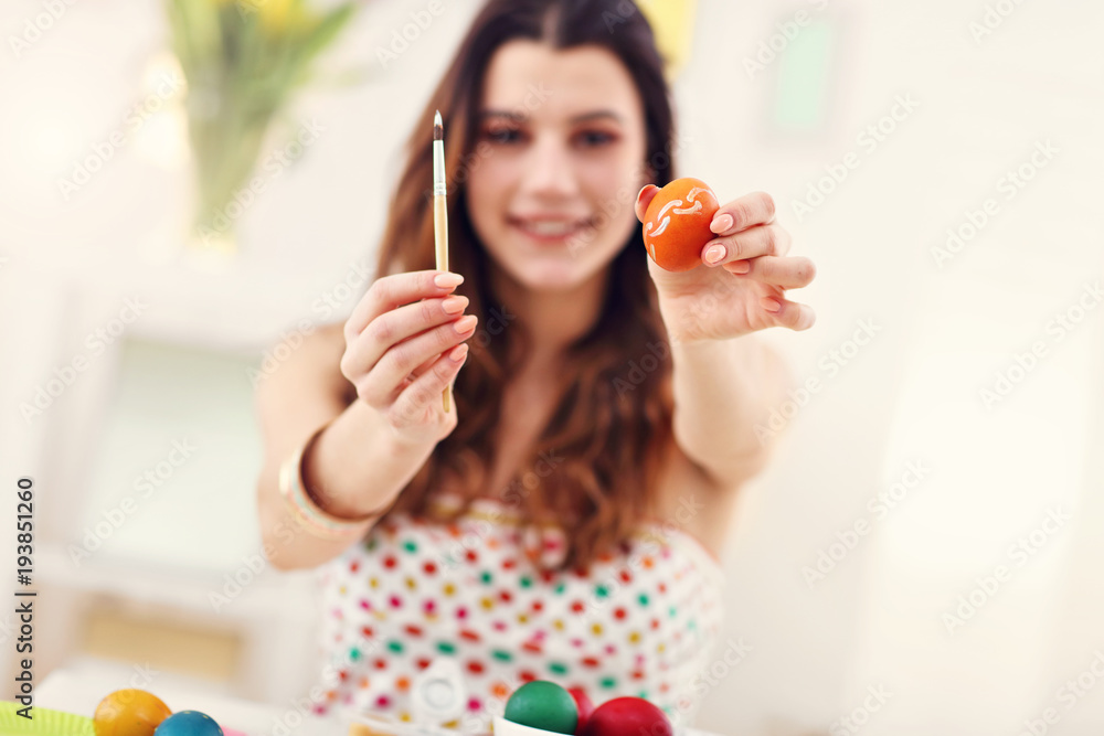 Attractive woman painting Easter eggs at home