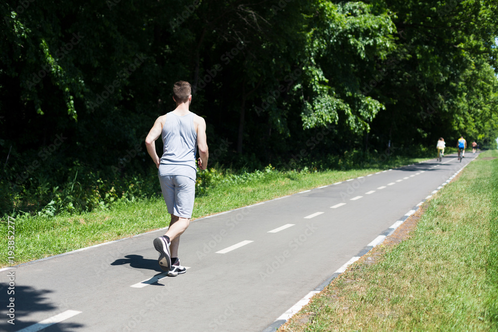 Young man jogging on treadmill in park, copy space Young man jogging on treadmill in park, copy space