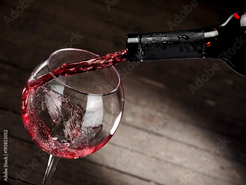 Red wine pouring in a glass on wood