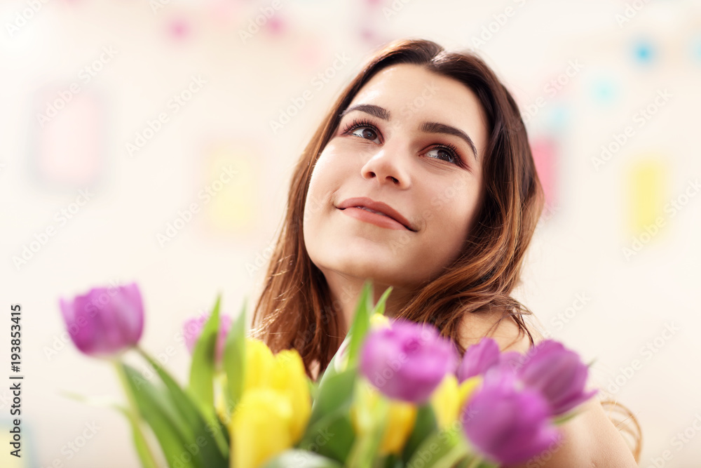 Attractive woman arranging tulips flowers in vase