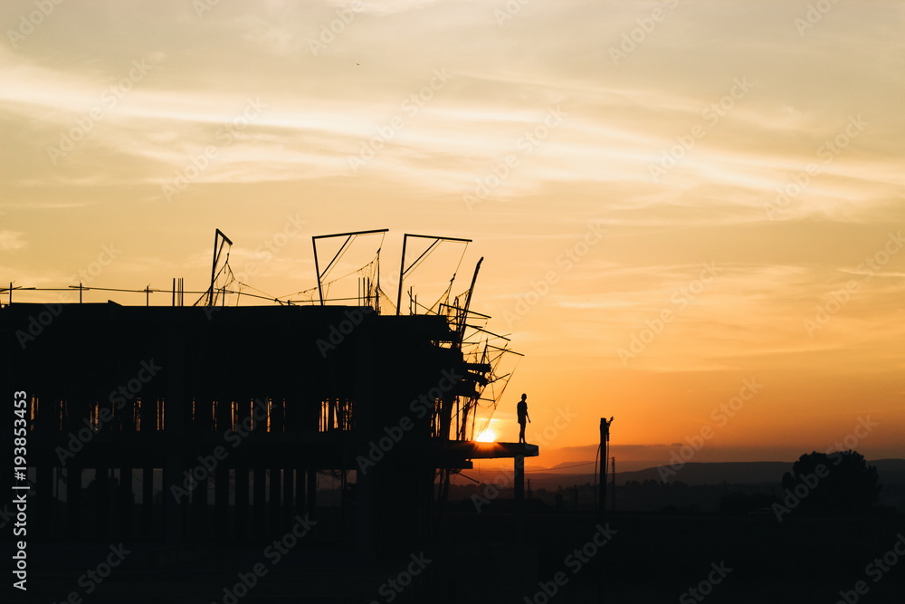 Construction site and a person in front of a sunset. Construction site and a person in front of a sunset.