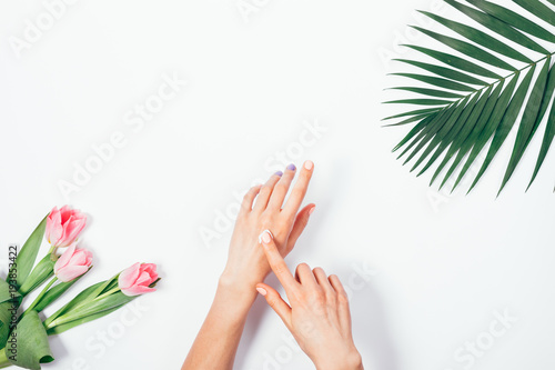 Cosmetic cream on female hands  palm branch and bouquet of pink tulips