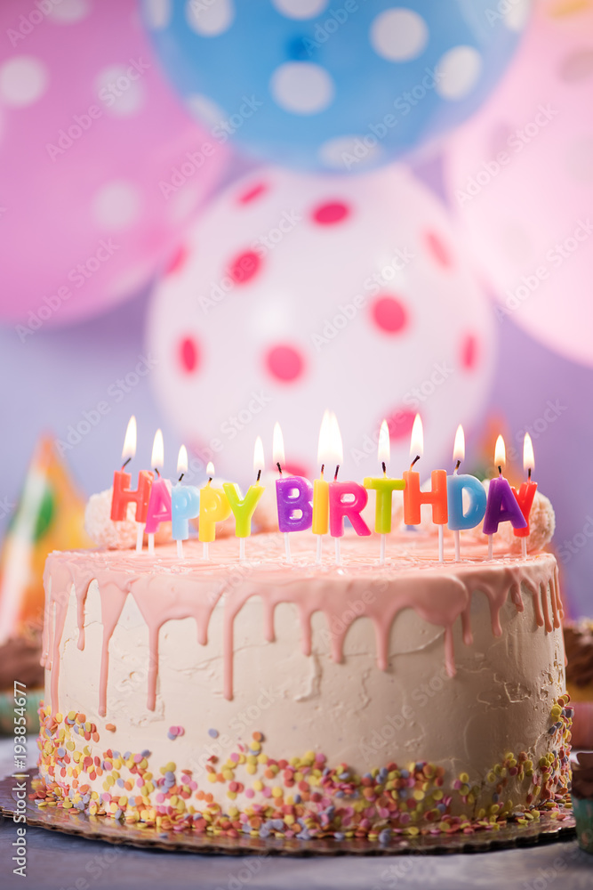 Foto Stock happy birthday candles on pink white birthday cake with coconut  balls balloon background | Adobe Stock