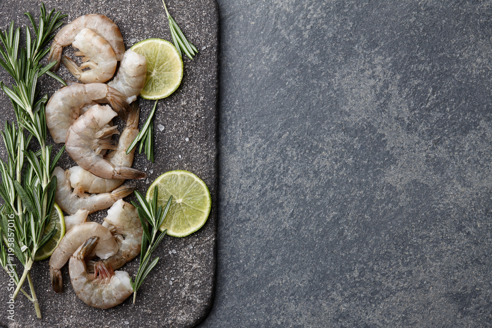 Cooking fresh raw tiger prawns with rosemary, lemon, lime, garlic and spices on stone countertop, top view Cooking fresh raw tiger prawns with rosemary, lemon, lime, garlic and spices on stone countertop, top view