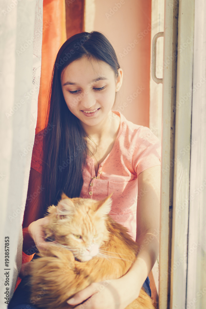 A girl is stroking a red cat. A girl is stroking a red cat.