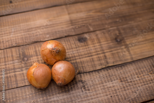 Three onions on wooden table. Place for text. Copy space