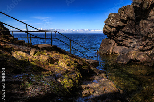 a stairway leading down to the water with rocks all around photo