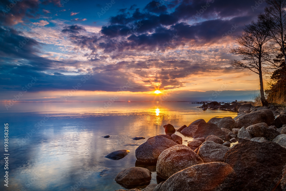 colorful sunset by a lake with a rocky beach colorful sunset by a lake with a rocky beach