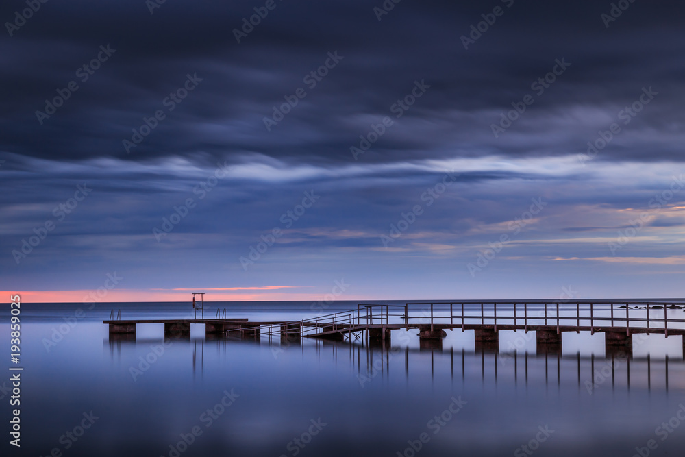 long pier leading into the ocean at sunset