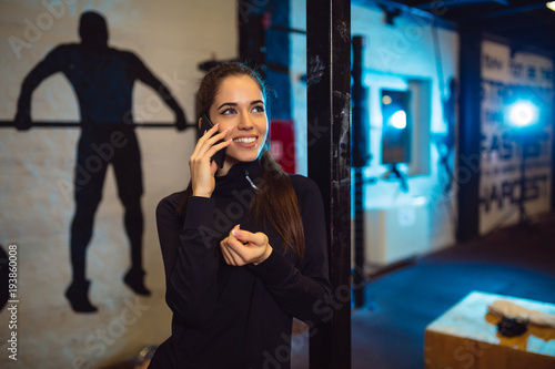 Sporty girl talking by the mobile phone in gym.