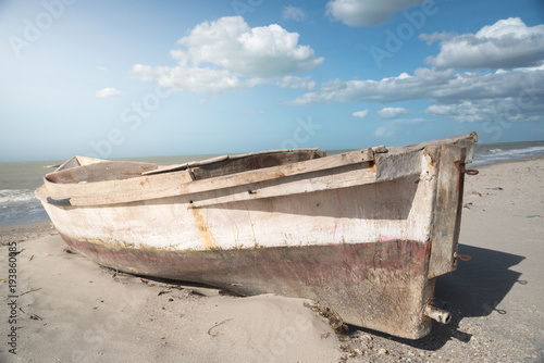 fisherman boat abandoned in the sand on the shore of the beach