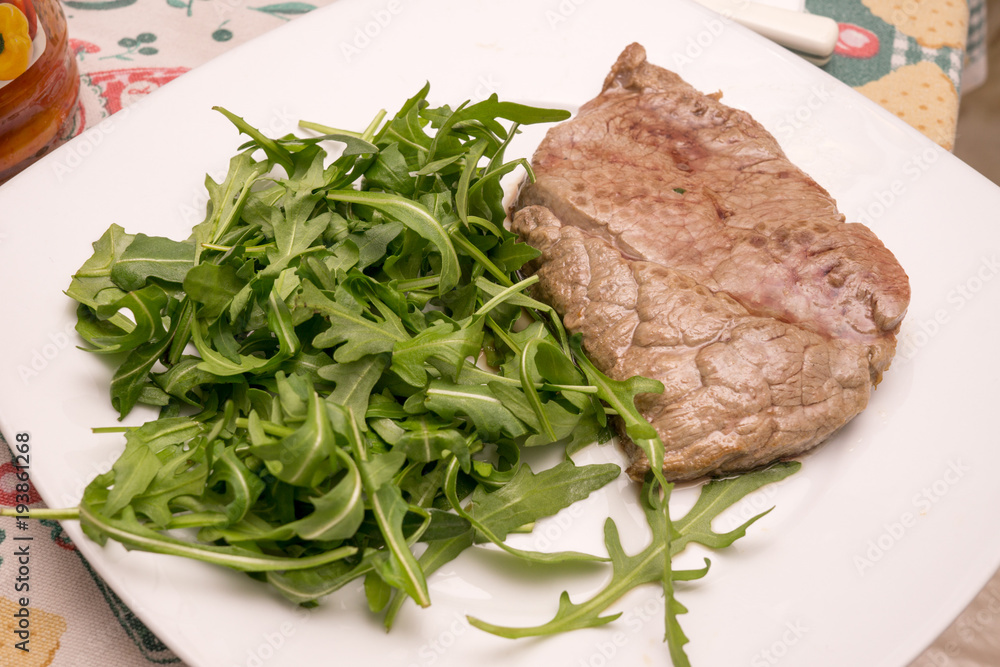 beef steak with rocket garnish, on white plate beef steak with rocket garnish, on white plate